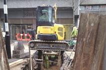 Digger over trench in high street